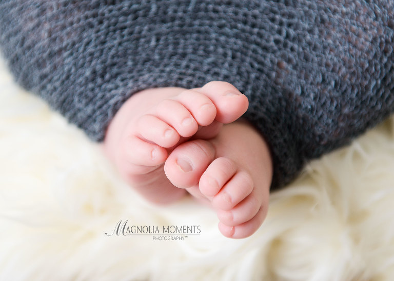 Newborn baby pic of toes close up with baby wearing newborn baby clothes of grey wrap during his newborn photography session by Evan Pollock one of the newborn photographers near me.