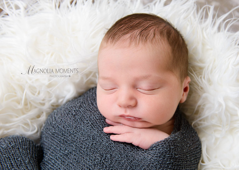 newborn baby boy wrapped in grey for his newborn photoshoot by Evan Pollock who does professional photography near me