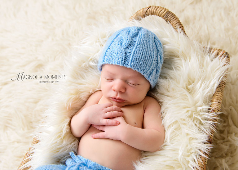 Close up of newborn baby boy in blue hat on fur photographed by Evan Pollock one of the newborn photographers near me. Yardley newborn photographer