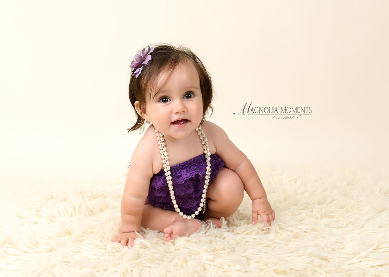 Adorable birthday girl in purple lace cake smash outfit for her first birthday session by Evan Pollock of Magnolia Moments Photography a professional photography studio near me