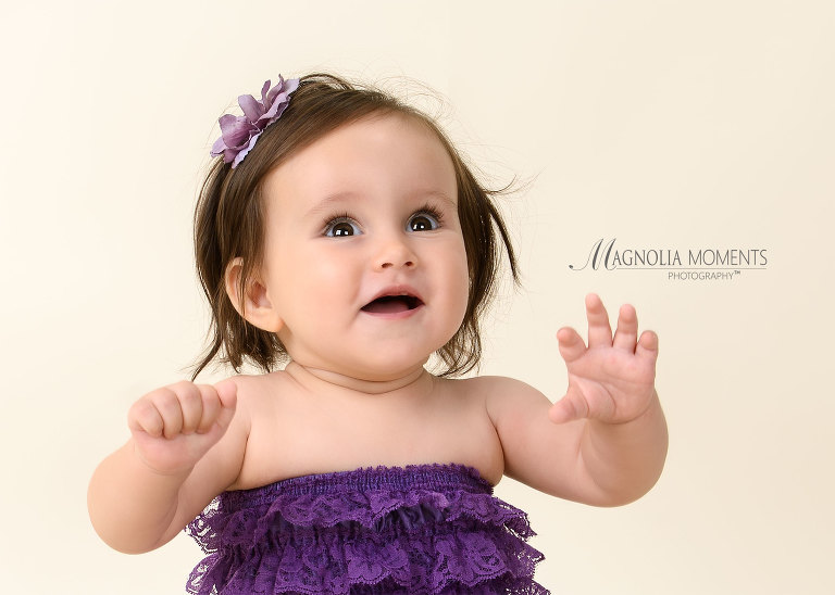 Dark haired one year old dressed in purple lace for her cake smash session by Evan Pollock of Magnolia Moments Photography one of the photography studios near me