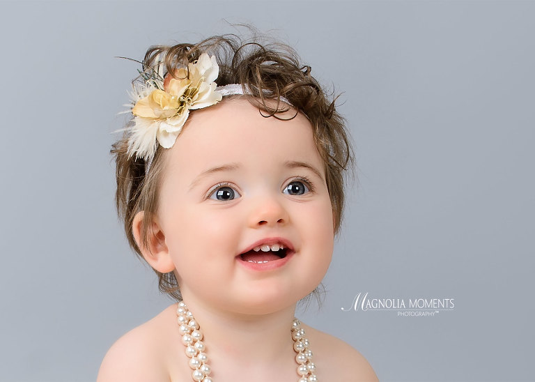 Close up of one year old girl in vintage headband part of her cake smash outfit for her 1st birthday portrait child portrait session by Magnolia Moments Photography in PA