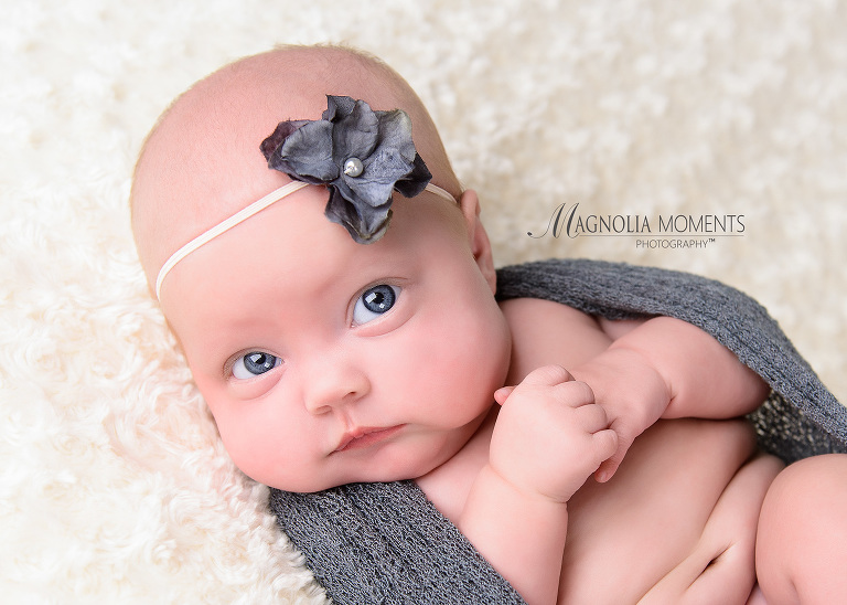 Closeup of baby girl with big blue eyes wrapped in grey for her newborn baby pic