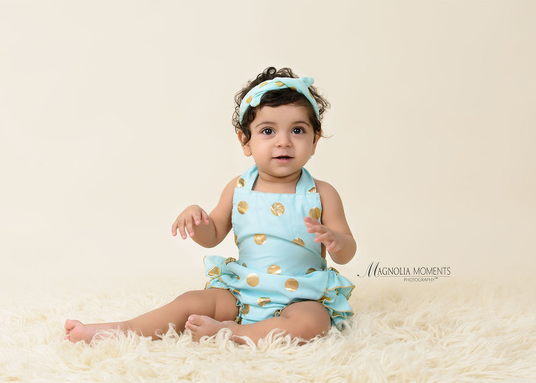 Beautiful birthday girl dressed in light blue dress for her Cake smash outfit during her 1st birthday cake smash photographed by Evan Pollock of Magnolia Moments Photography. Lansdale child photographer