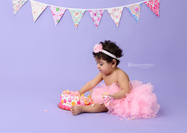 Sweet baby girl in pink tutu on lavender backdrop with birthday cake photographed by Evan Pollock of Magnolia Moments Photography one of the professional photographers near me. Lansdale child photographer