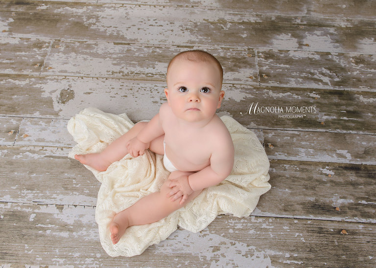Adorable baby boy on barn floor with cream blanket during his cake smash portrait session by Evan Pollock of Magnolia Moments Photography one of the photographers near me. Philadelphia baby photographer