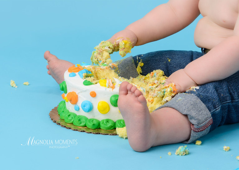 Close up of feet and birthday cake on blue background during smash cake session by Evan Pollock of Magnolia Moments Photography a photography studio near me. Philadelphia baby photographer