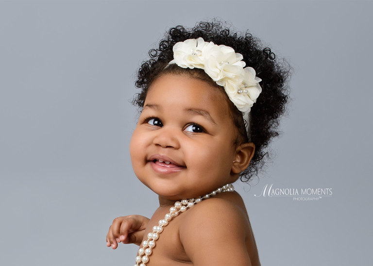 Closeup of beautiful baby girl in cream headband photographed by Evan Pollock of Magnolia Moments Photography for her 1st birthday cake smash.