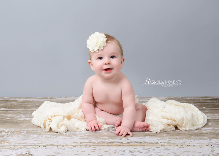 Baby girl in cream headband on barn floor with cream blanket photographed by Evan Pollock of Magnolia Moments Photography who does baby photography near me. Mont Clare baby photographer.
