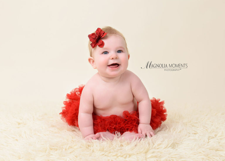 Precious baby girl in red tutu and flower headband photographed on cream fur by Evan Pollock of Magnolia Moments Photography one of the photography studios near me. Mont Clare baby photographer.